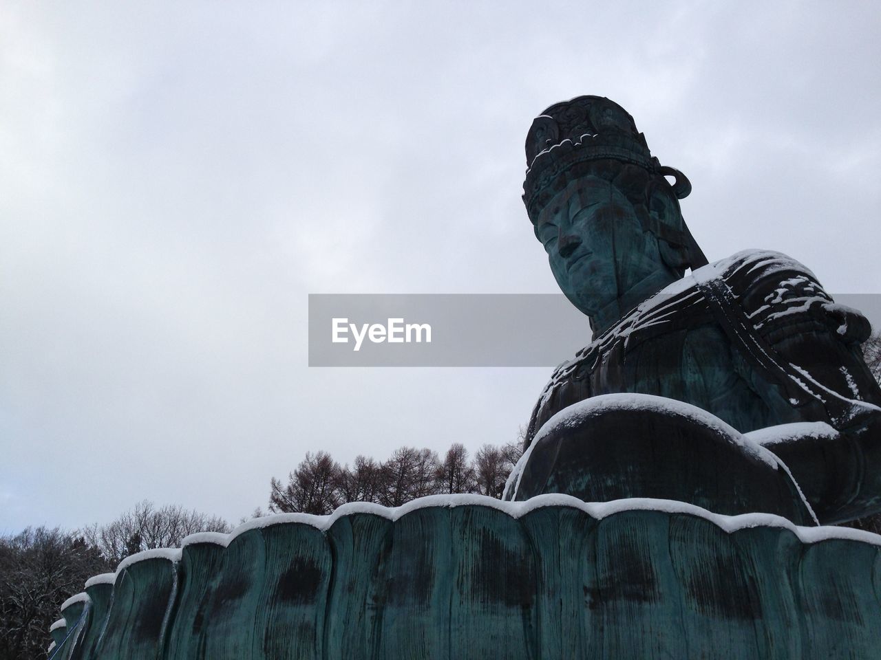 Low angle view of statue against sky during winter