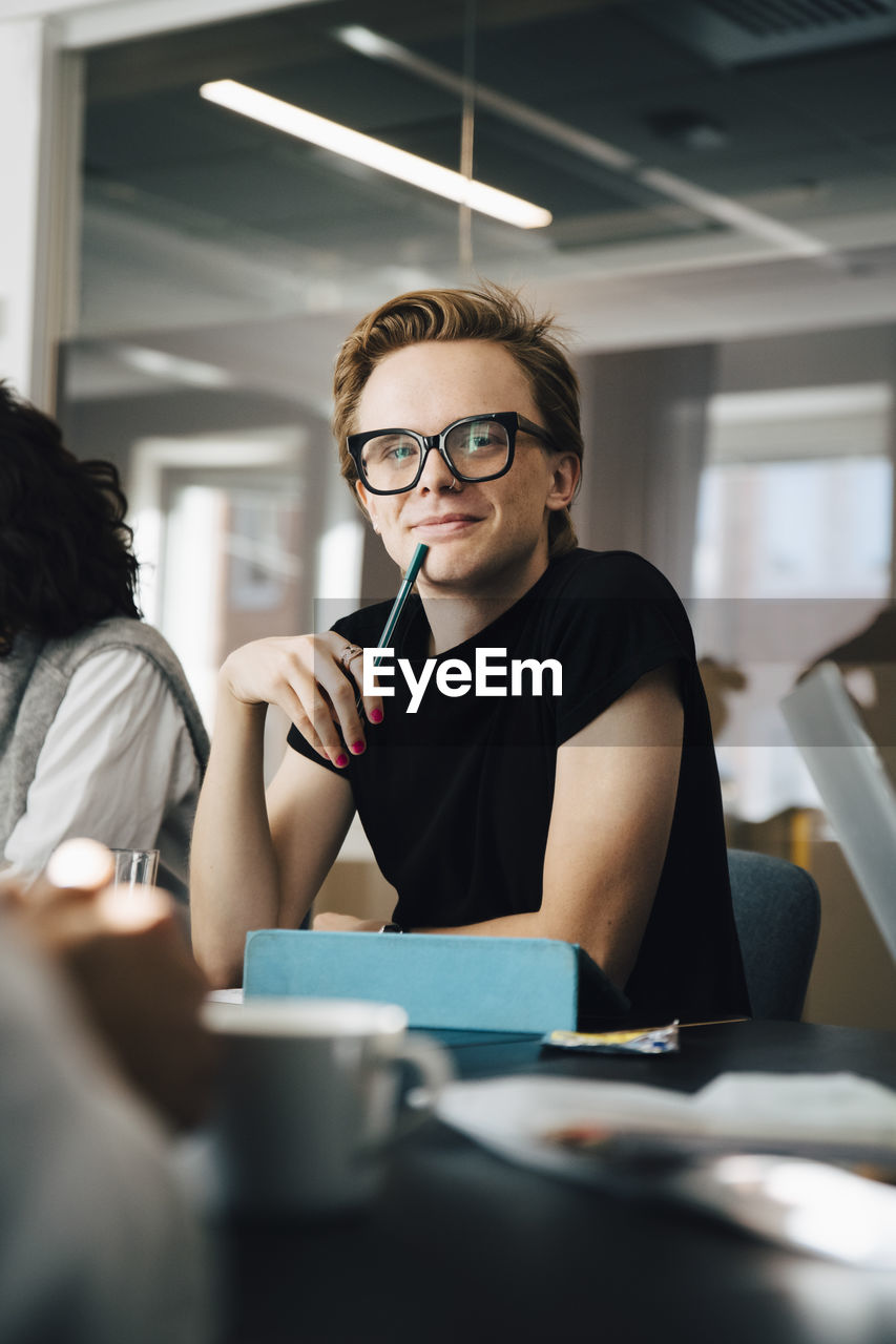 Businesswoman discussing with transgender colleague over laptop in board room during meeting