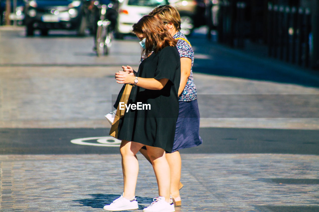 WOMAN STANDING ON STREET AGAINST CITY