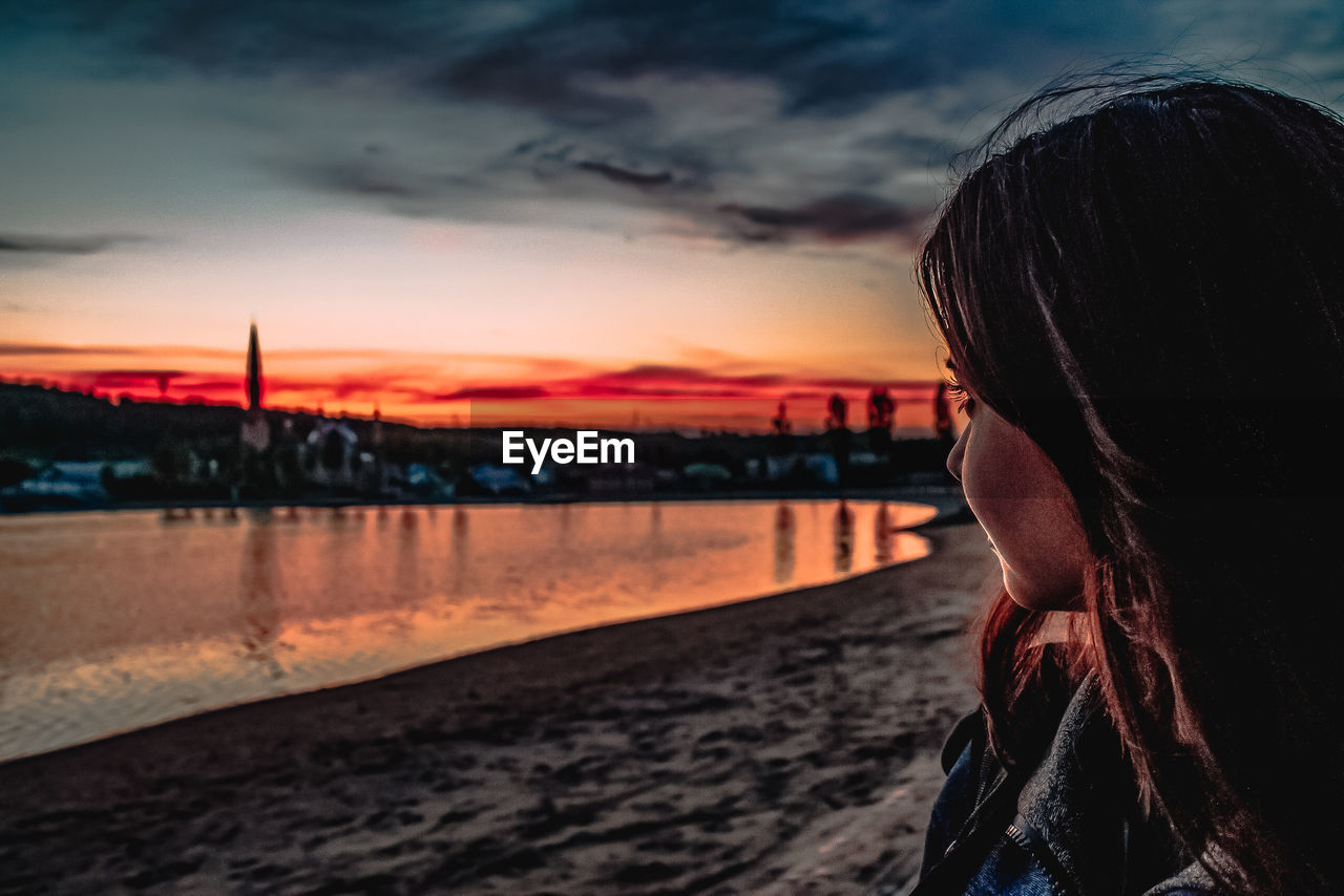 Portrait of woman on beach against sky during sunset