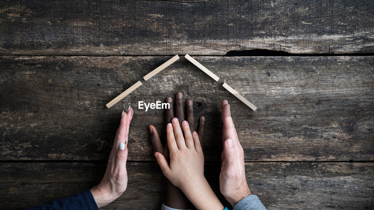 HIGH ANGLE VIEW OF HANDS ON TABLE AGAINST WALL