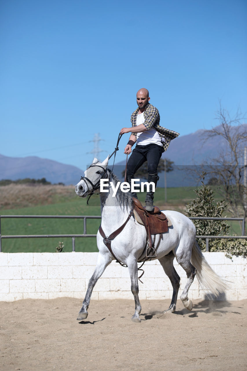 Full length of man standing on horse against sky