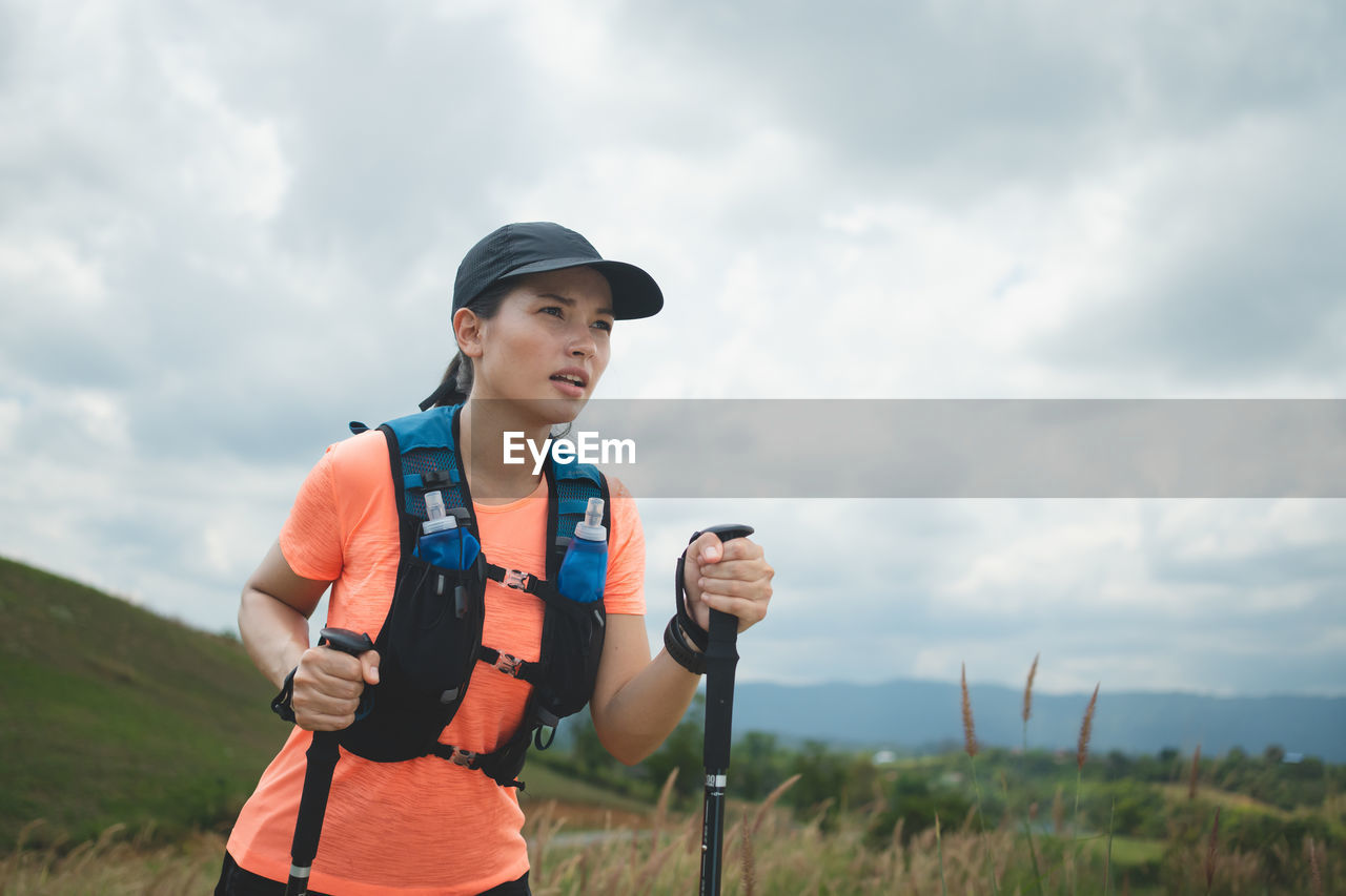 side view of young man standing against cloudy sky