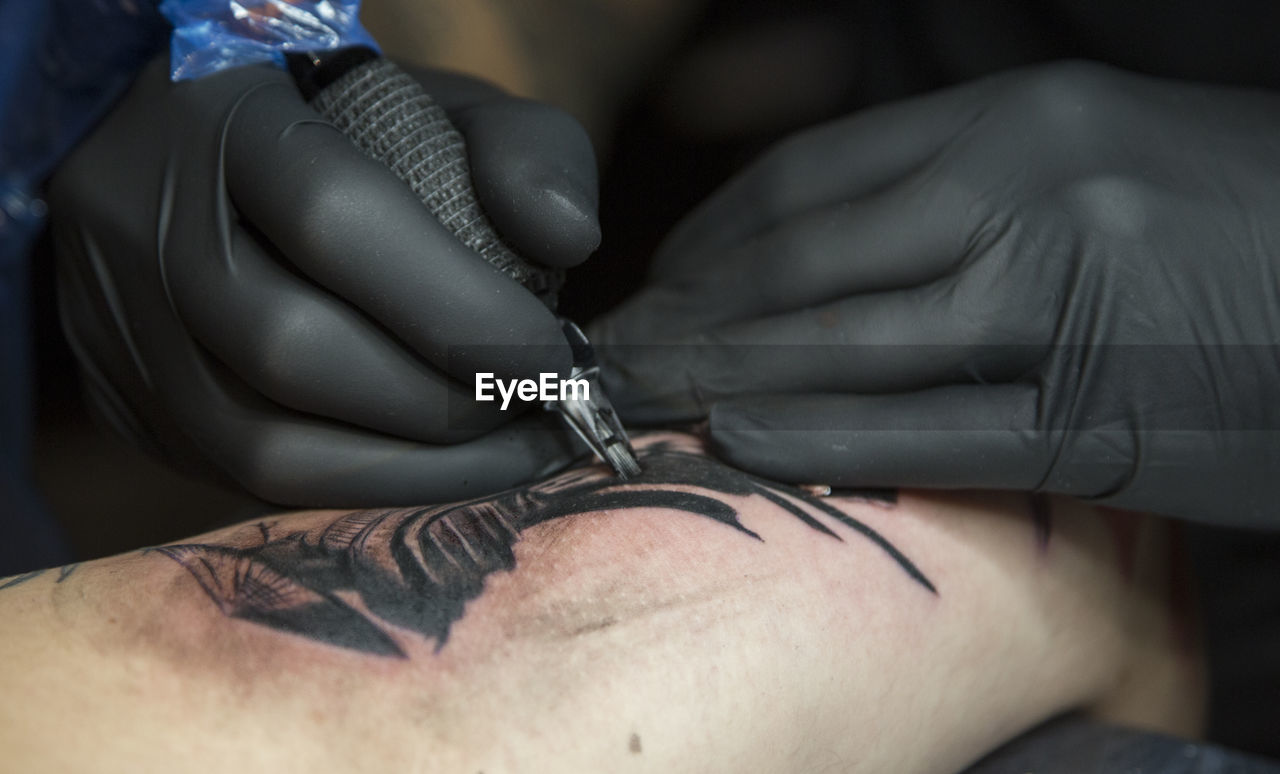 Cropped image of artist making tattoo of man hand