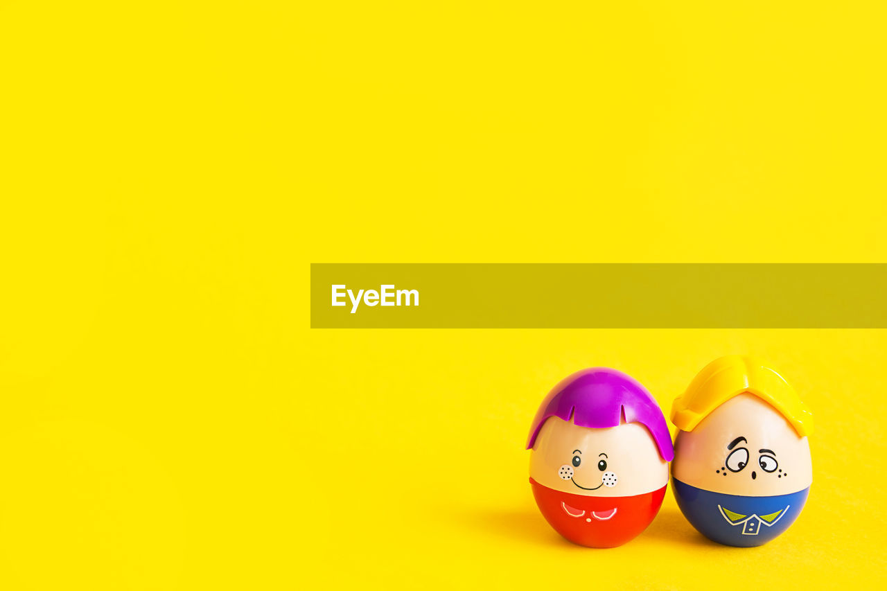 Two funny eggs boy and girl with faces on a yellow background - easter, spring. children