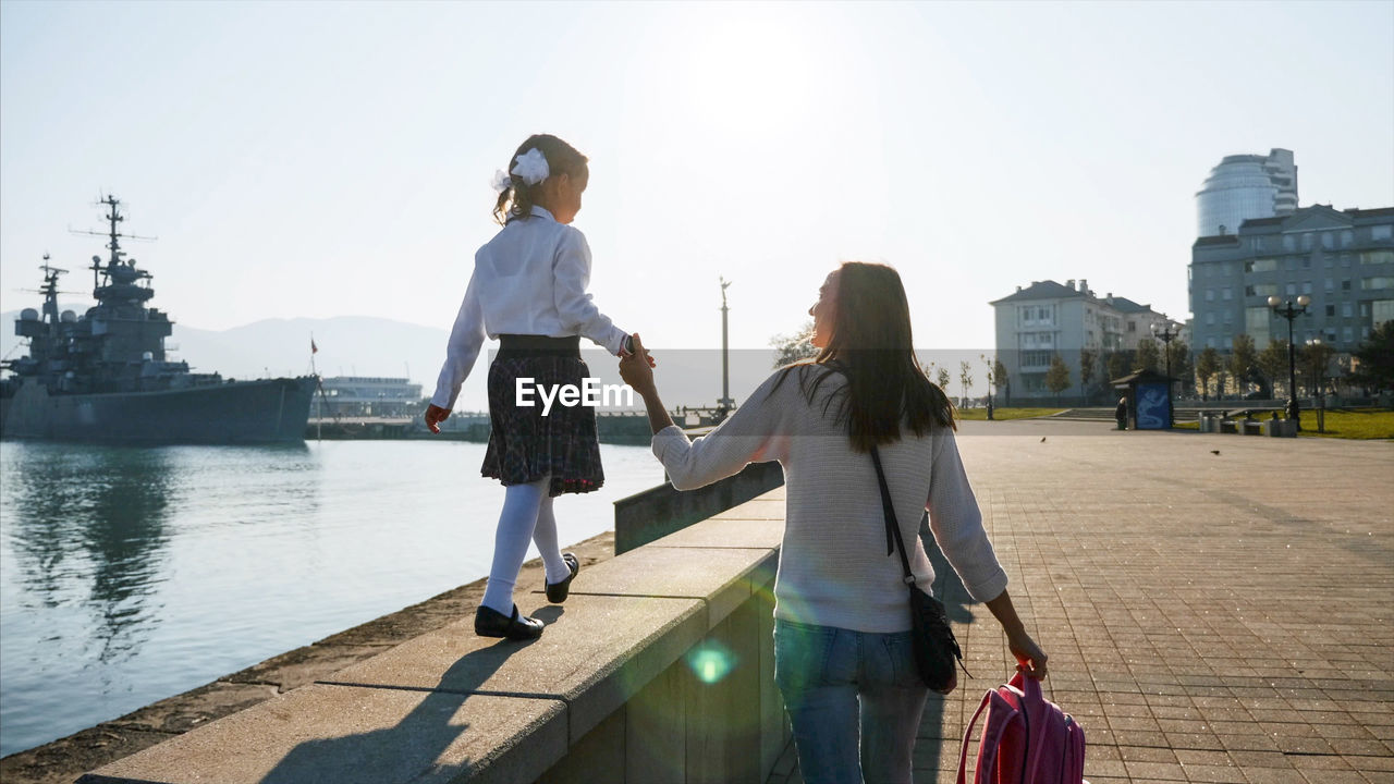 Rear view of mother with daughter walking in city