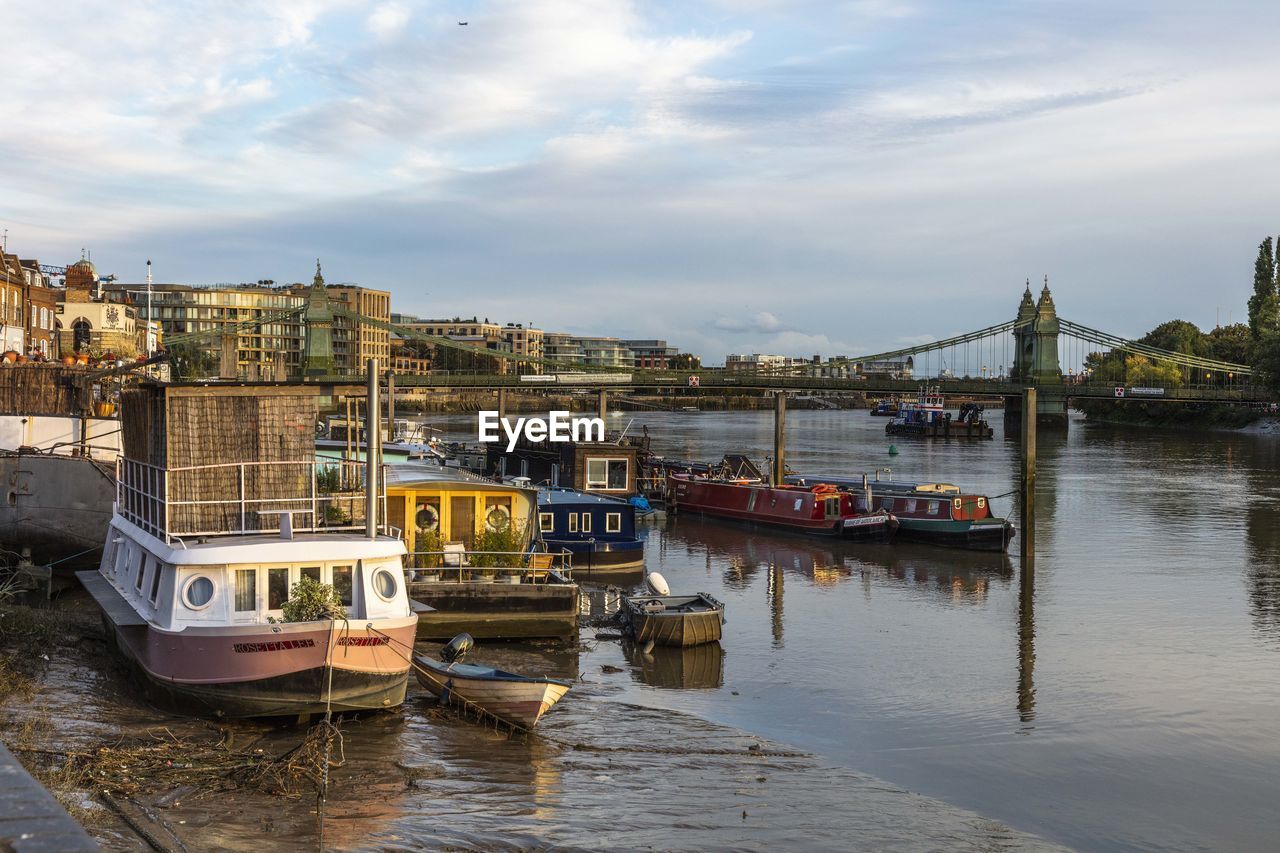 Boats moored in river against sky in city