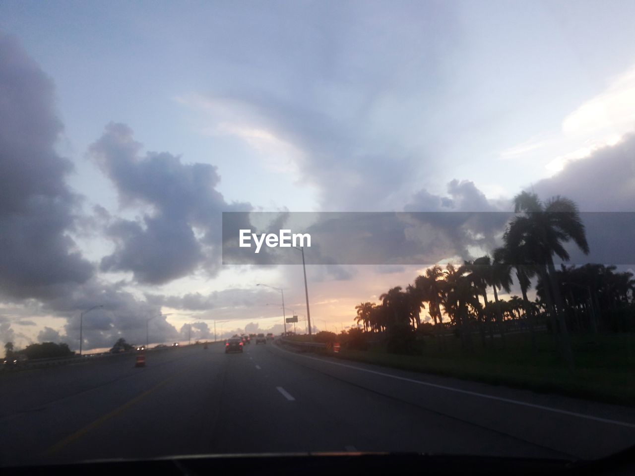 CARS ON ROAD AGAINST SKY DURING SUNSET
