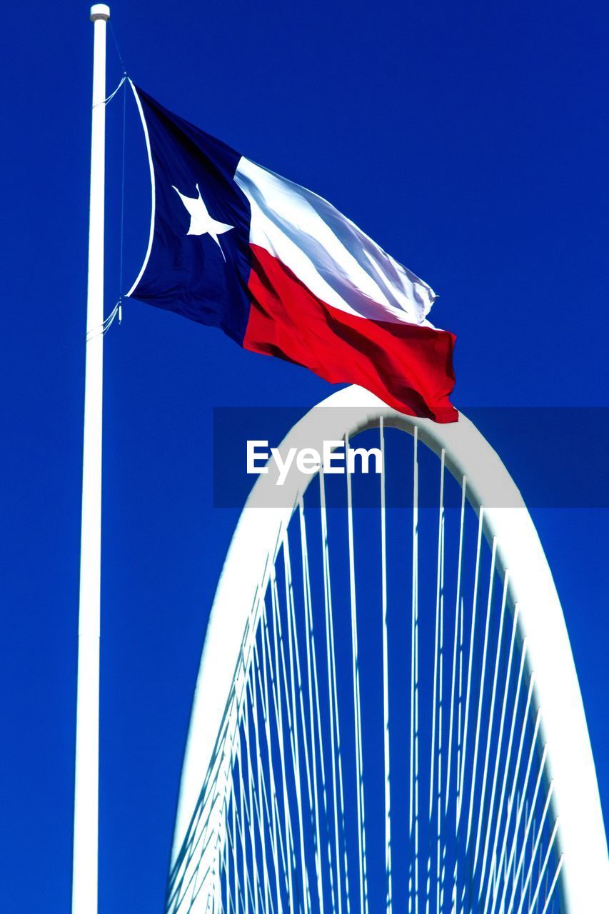 LOW ANGLE VIEW OF FLAGS AGAINST BLUE SKY