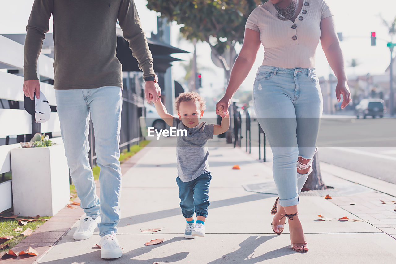 Family of three walking in downtown, baby boy walking with parents