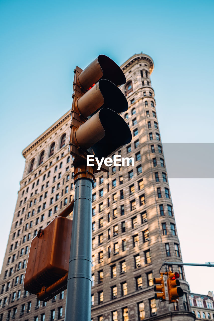 Low angle view of building and traffic light against sky