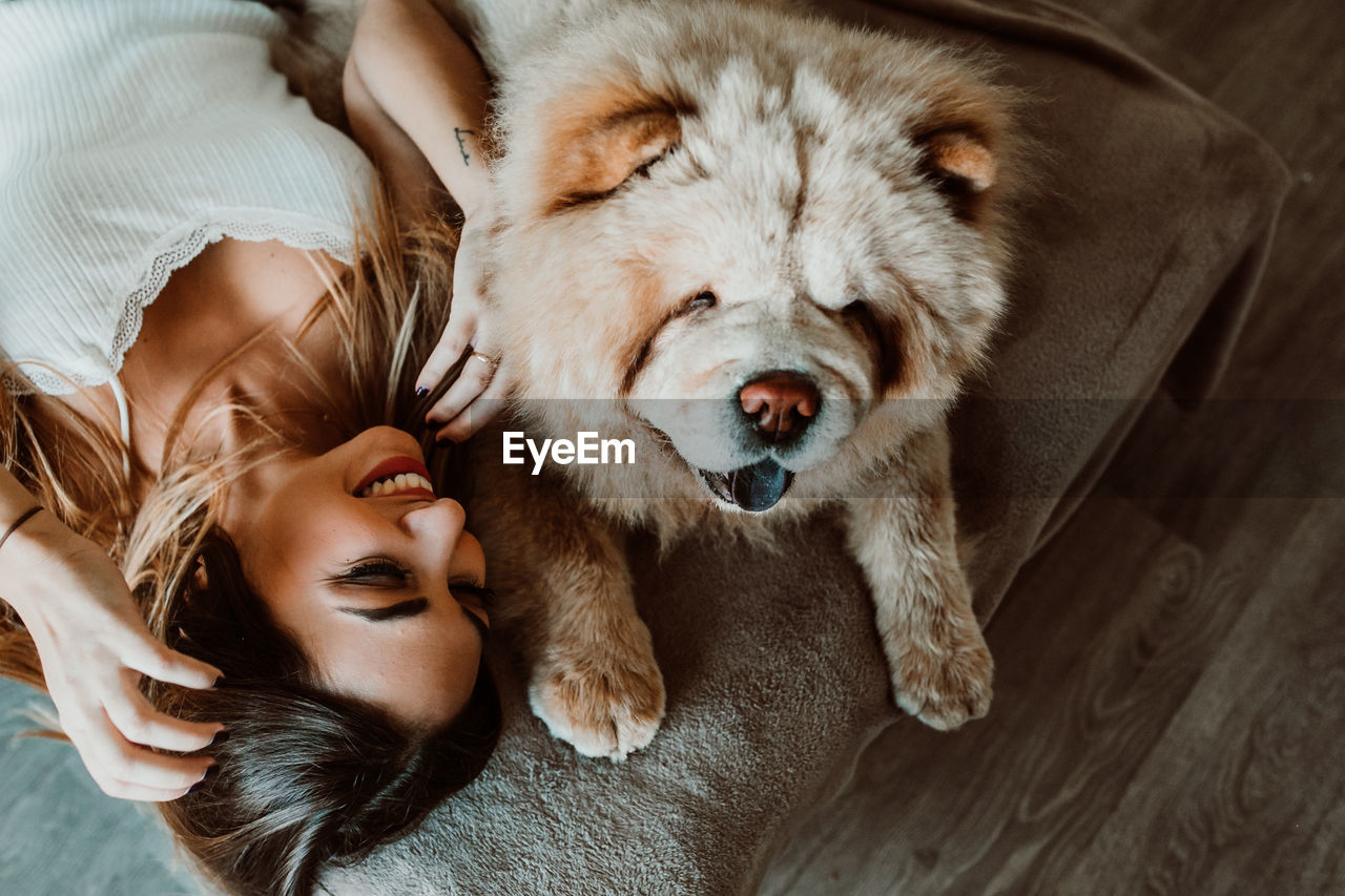 High angle view of young woman with dog lying on bed at home