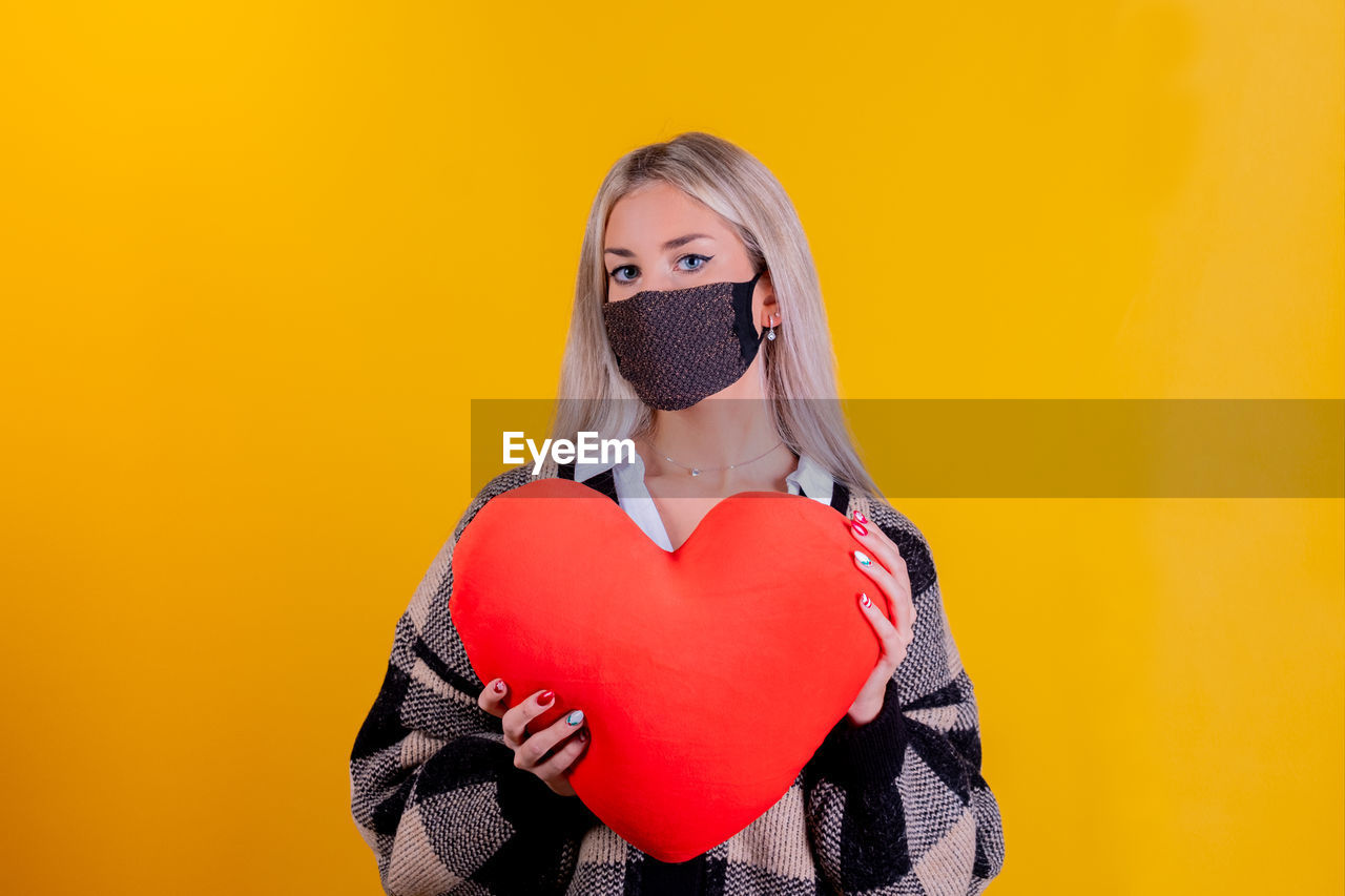PORTRAIT OF WOMAN WITH HEART SHAPE OVER YELLOW BACKGROUND