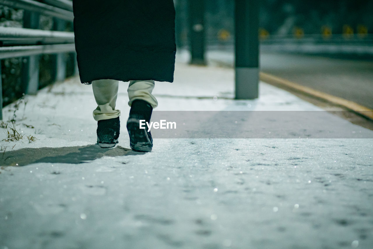 Low section of woman walking on road