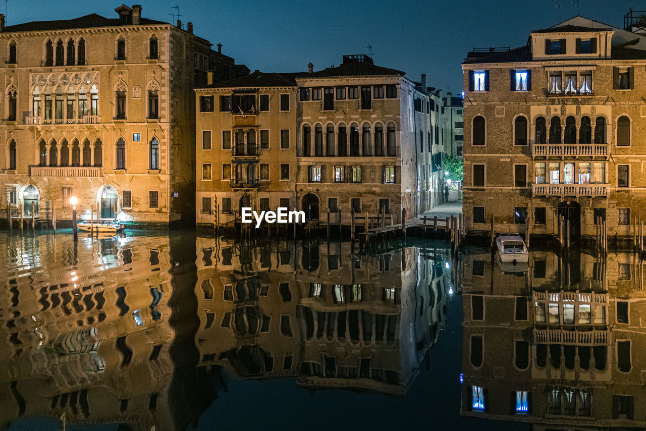Reflection of illuminated buildings on the grand canal in venice at night.