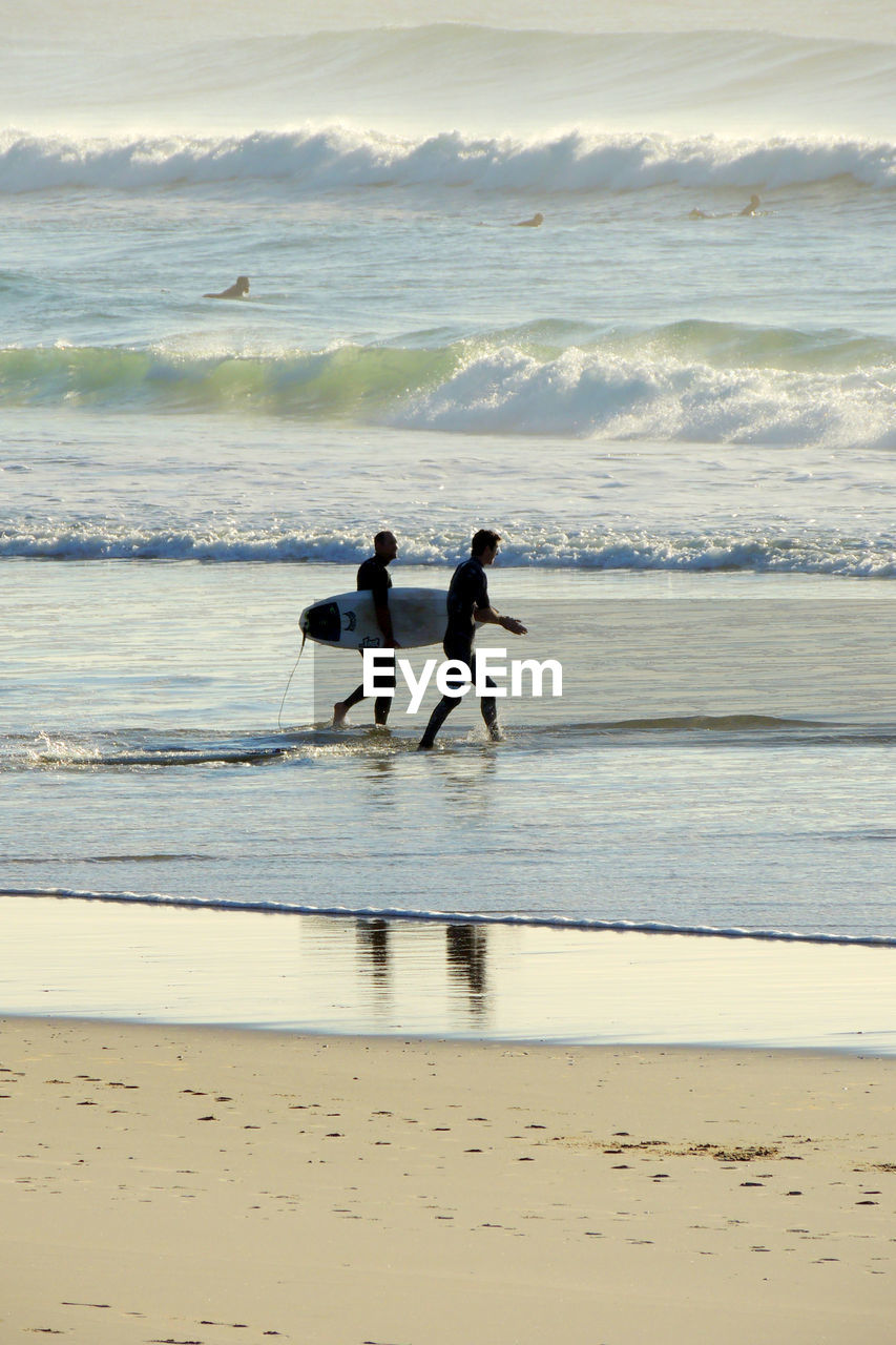 MEN ON BEACH AGAINST SKY