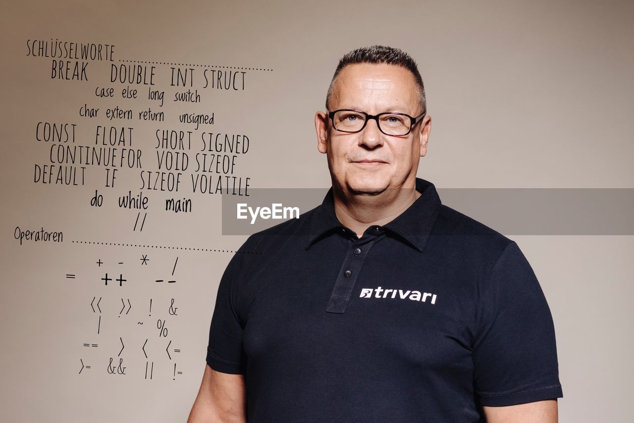 Portrait of confident muscular man standing against whiteboard