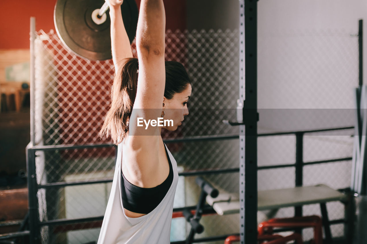 Female athlete exercising with barbell in gym