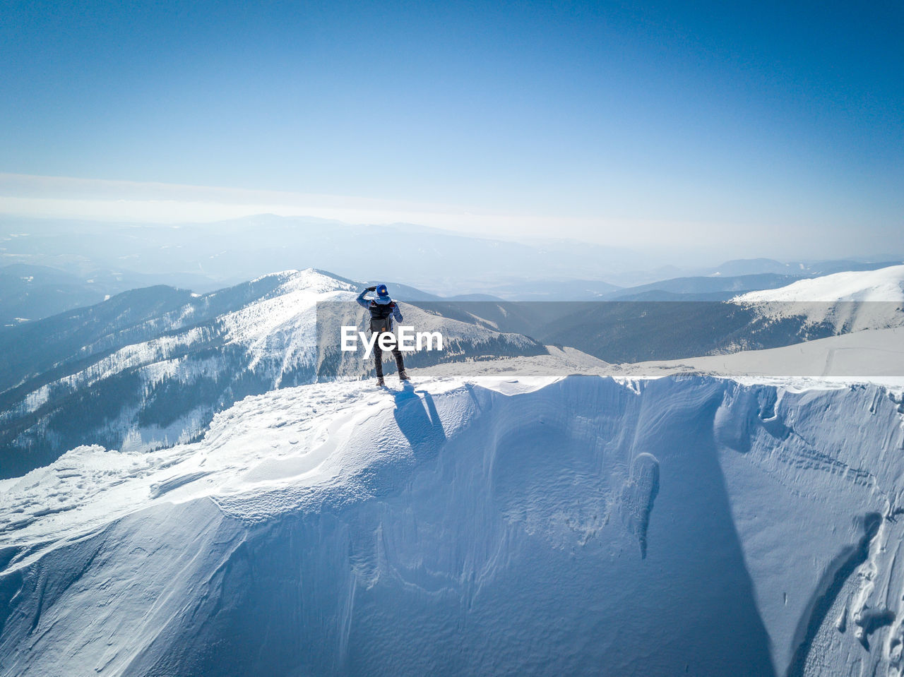 Rear view of man standing on snowcapped mountain