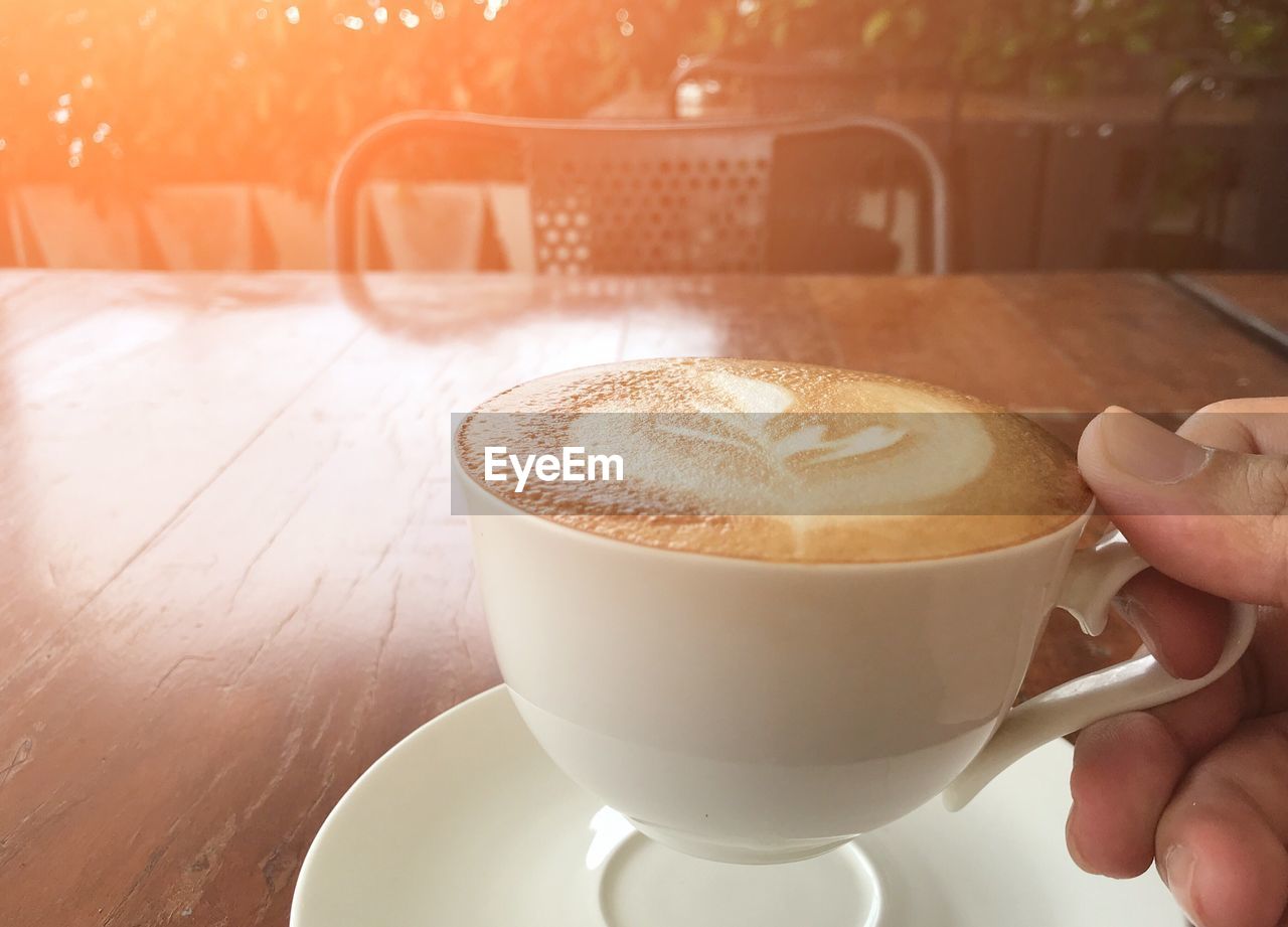 CROPPED IMAGE OF PERSON HOLDING COFFEE CUP WITH SPOON
