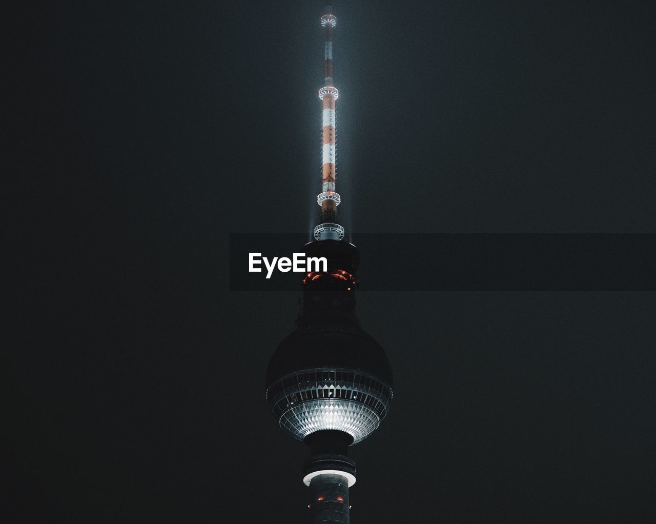 Illuminated fernsehturm against sky at night