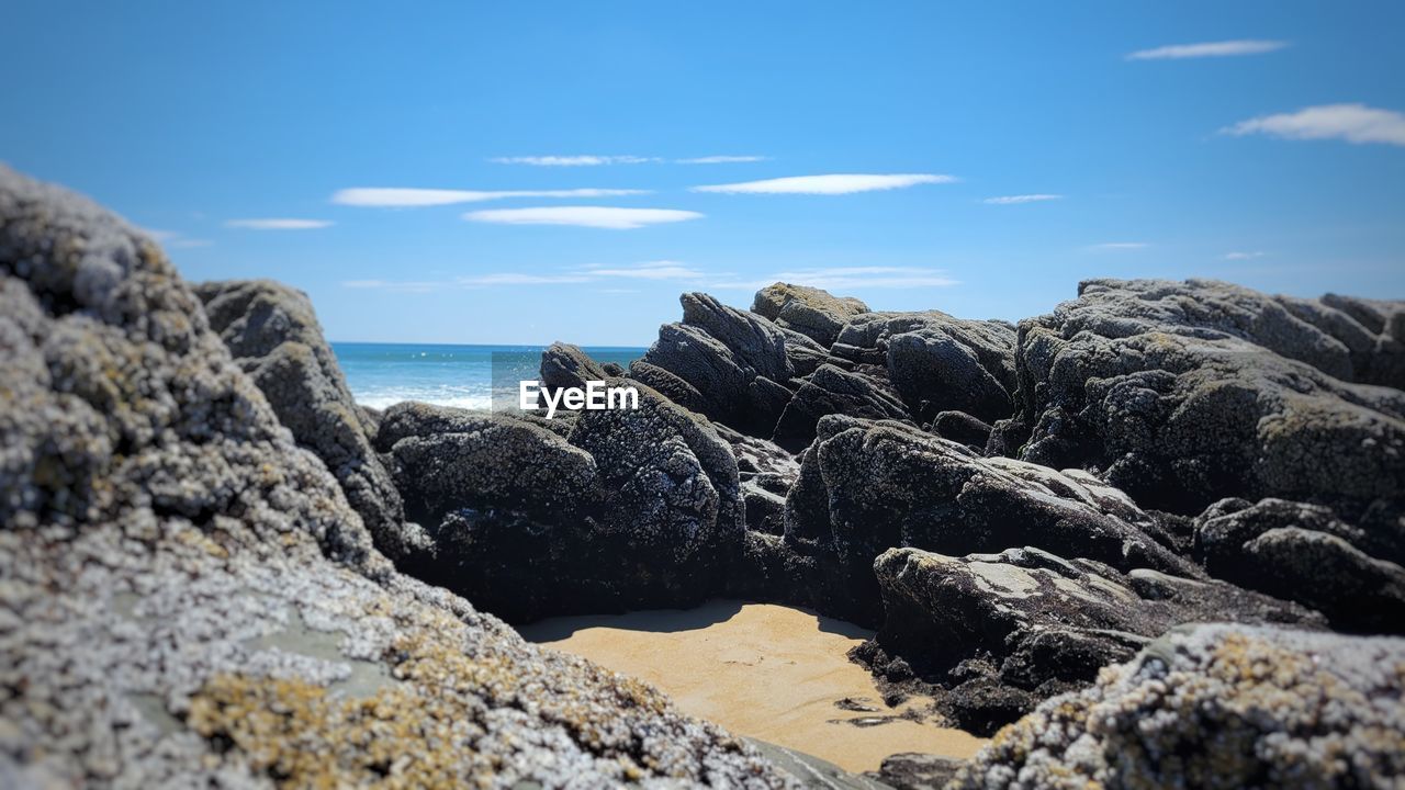 ROCKS ON SHORE AGAINST SKY