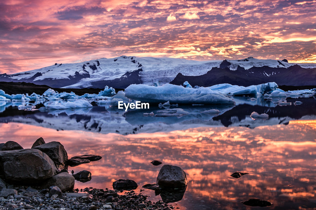 Scenic view of frozen lake against cloudy sky during sunset