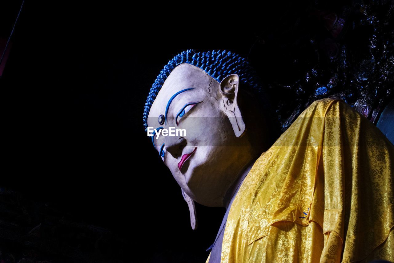 Low angle view of buddha statue against dark sky
