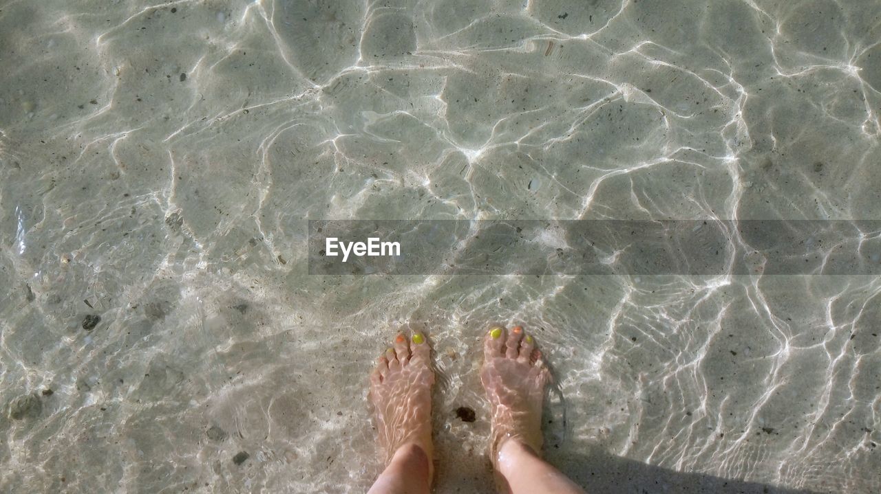 LOW SECTION OF WOMAN SWIMMING IN SEA