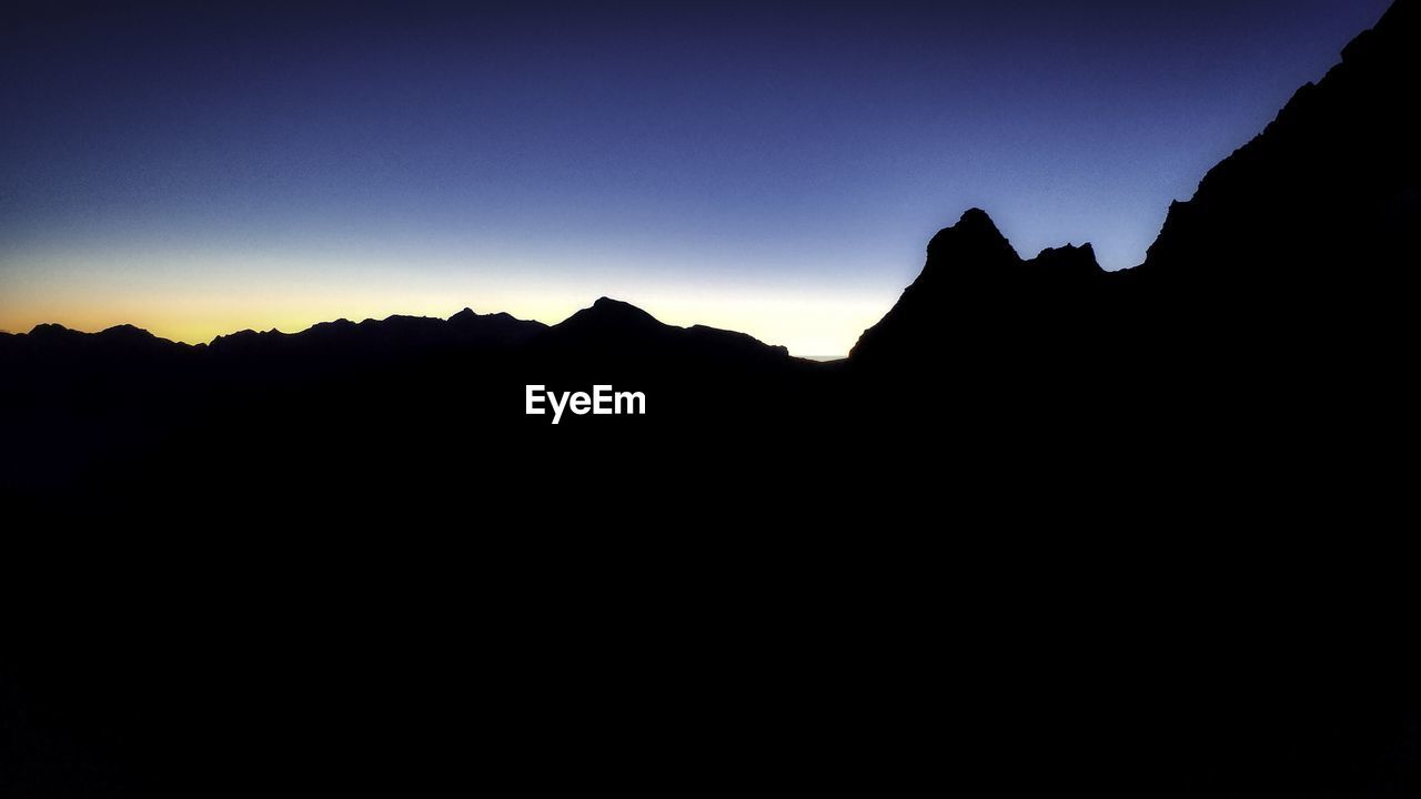 SILHOUETTE MOUNTAIN RANGE AGAINST CLEAR SKY AT SUNSET