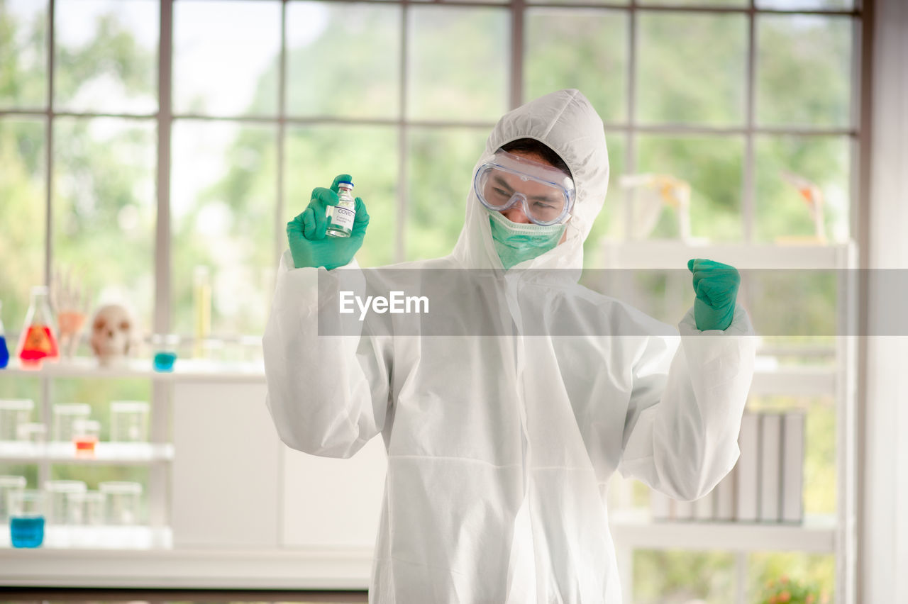 Smiling doctor wearing protective mask standing in laboratory