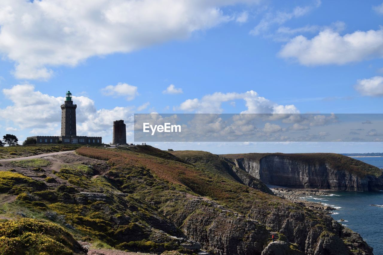 Lighthouse by sea against sky