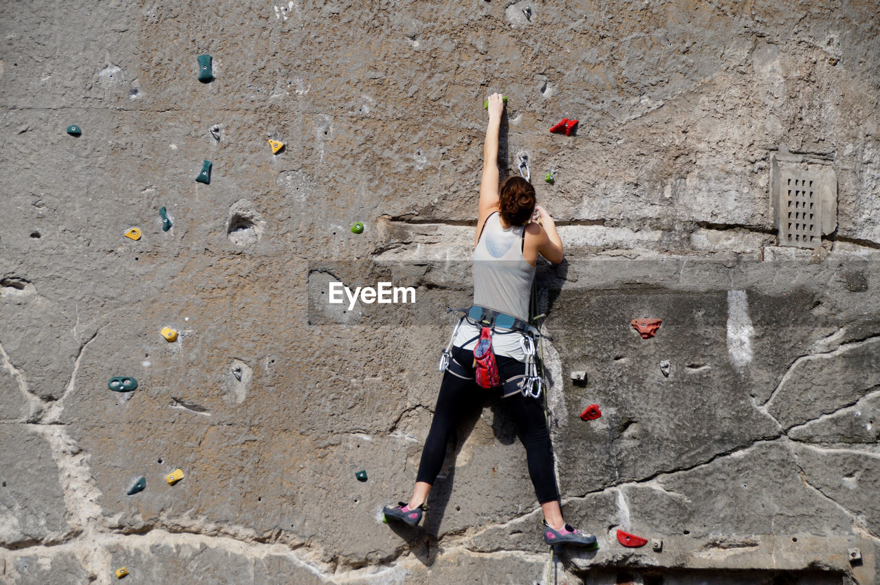 Low angle view of woman climbing wall