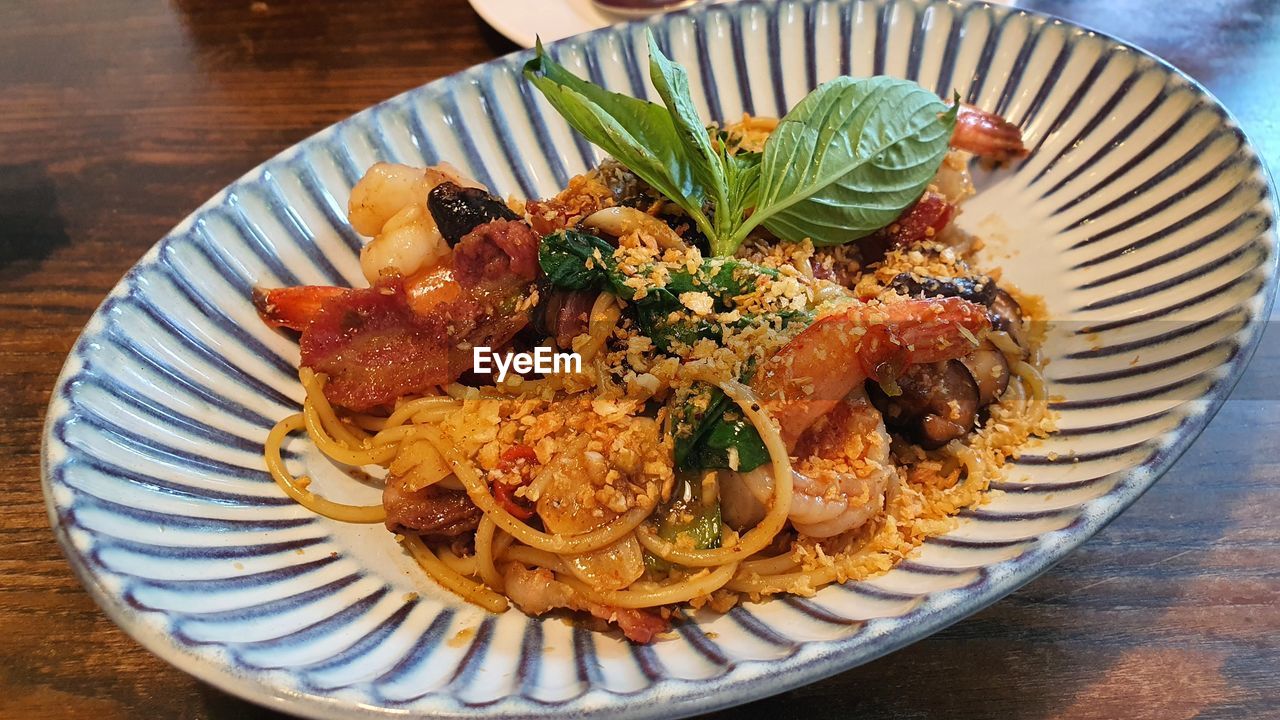 food and drink, food, plate, freshness, dish, table, healthy eating, cuisine, spaghetti, wellbeing, indoors, serving size, pasta, high angle view, no people, meal, italian food, vegetable, produce, still life, seafood, close-up, meat, fork, herb, wood, garnish
