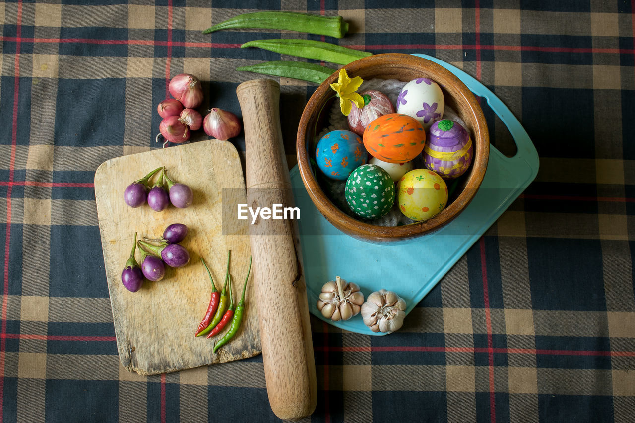 High angle view of multi colored easter eggs and vegetables on table