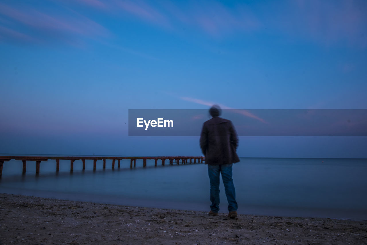 Rear view of man looking at sea against sky