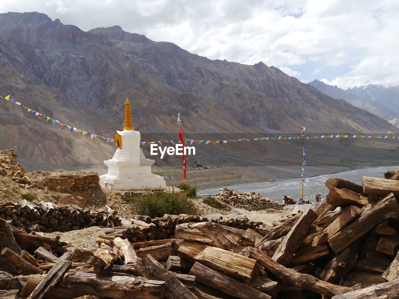 Logs by temple against rocky mountains