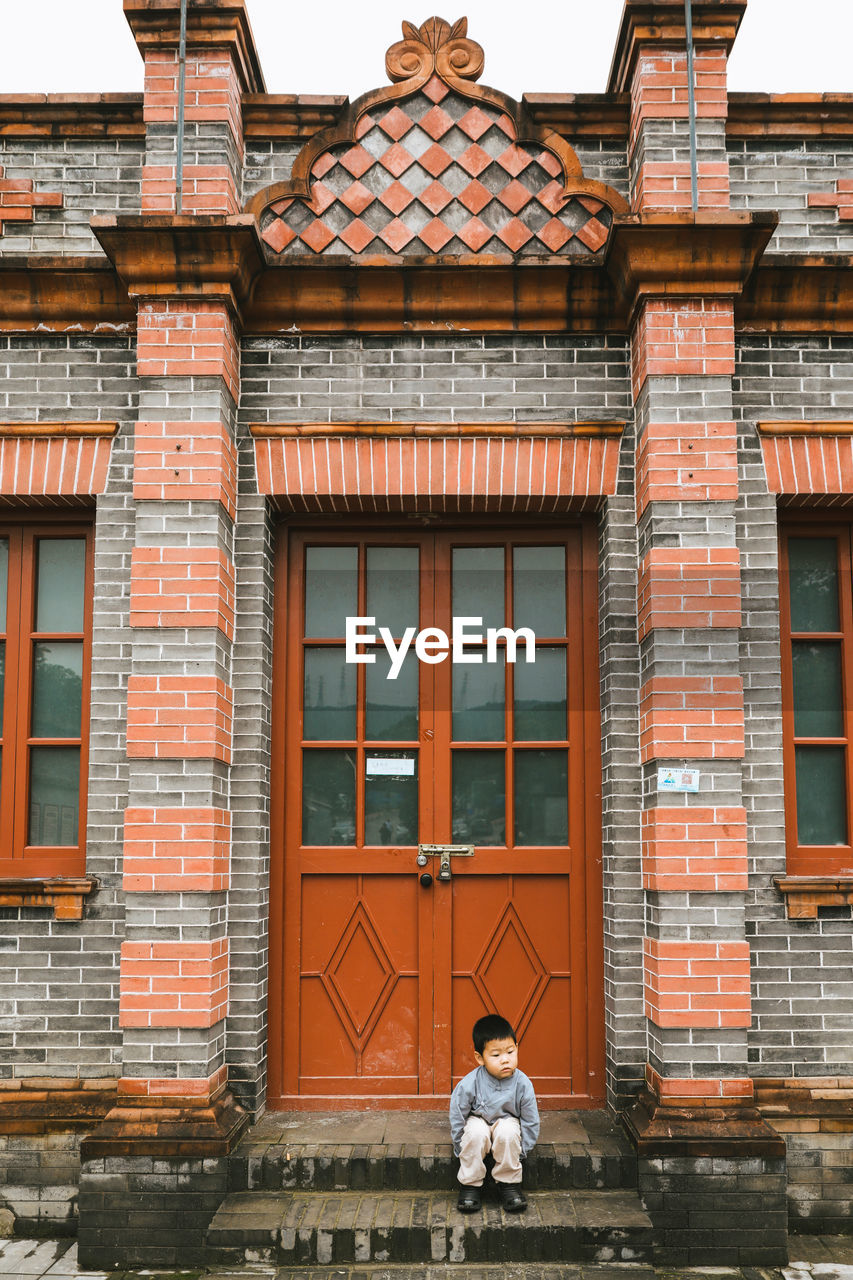 Cute boy sitting by door