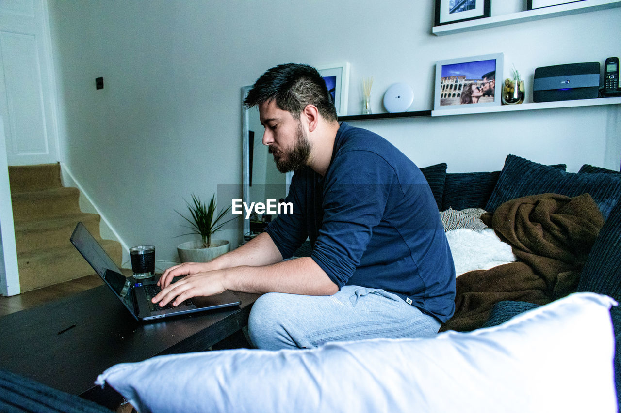 YOUNG MAN USING PHONE AT HOME