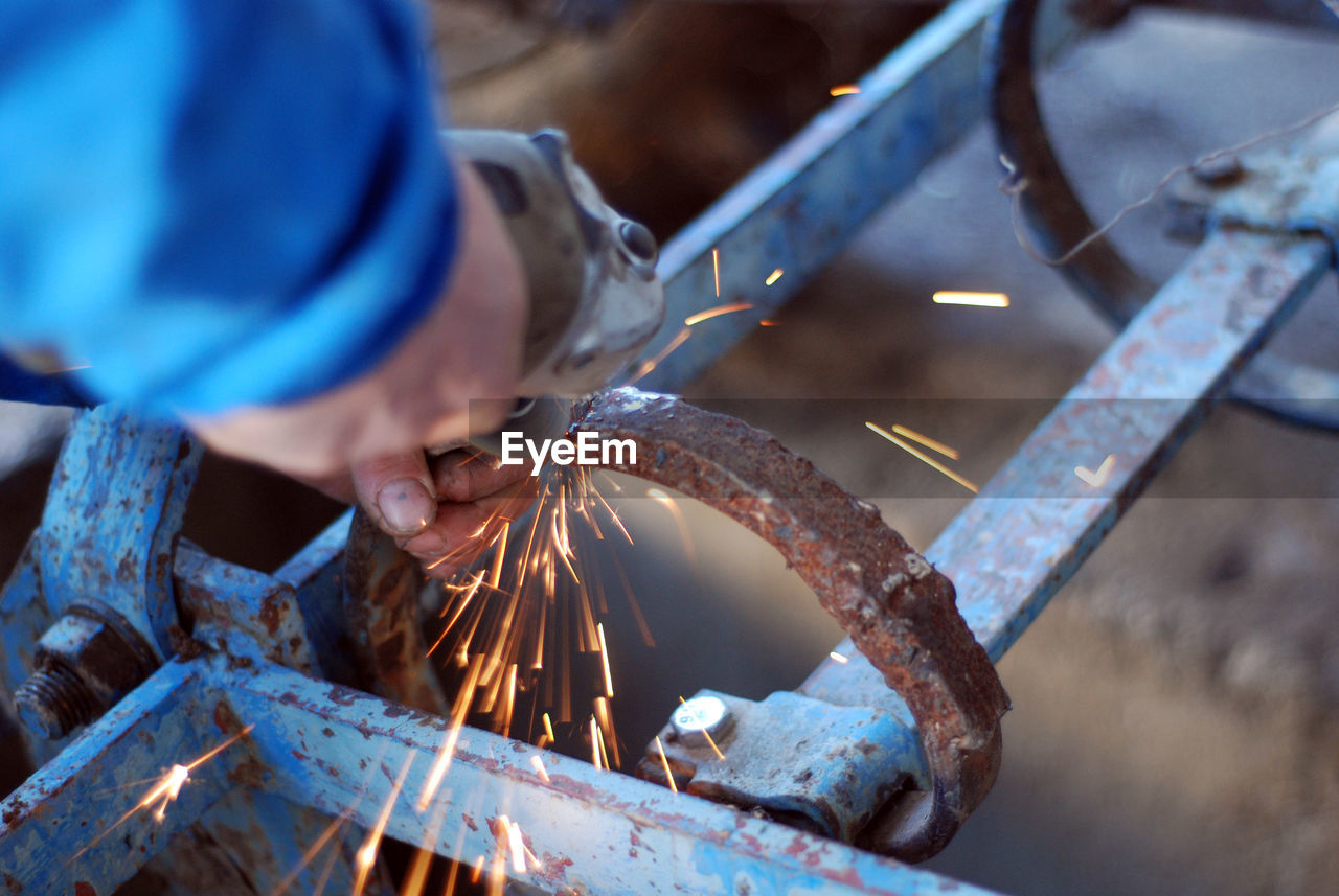 Cropped hand cutting rusty metal at workshop