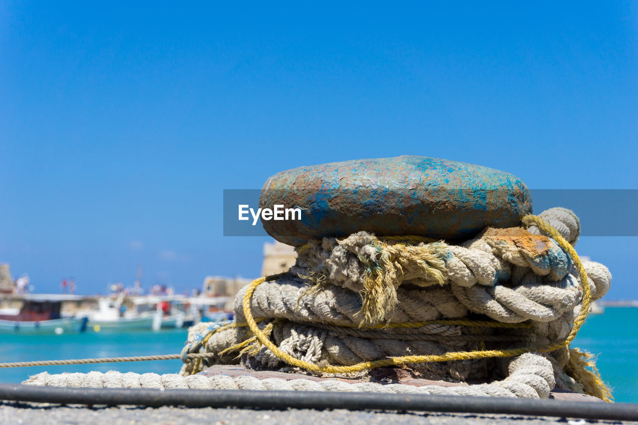 CLOSE-UP OF ROPE TIED ON BOAT MOORED AT HARBOR