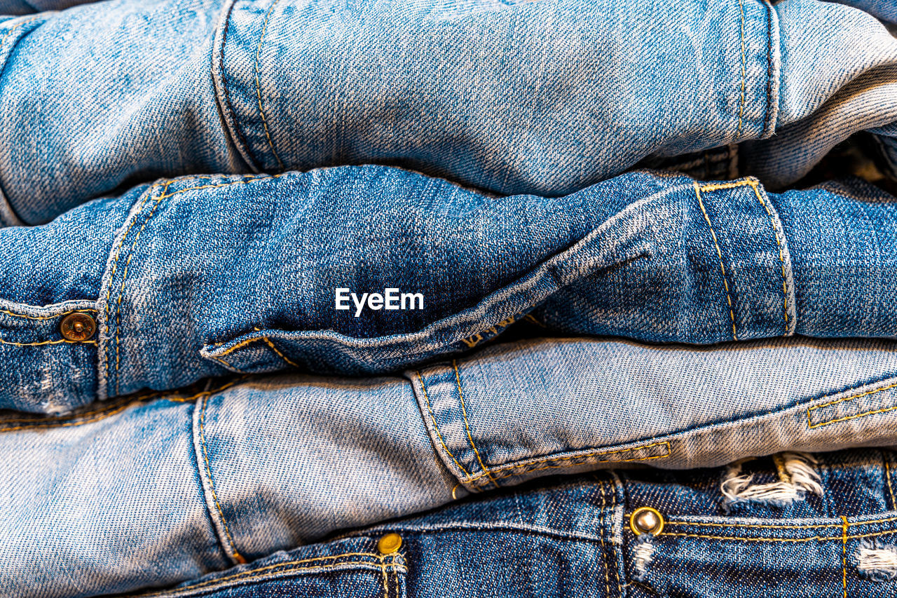 Stack of jeans of various shades of blue inside a closet - denim can be used as a background