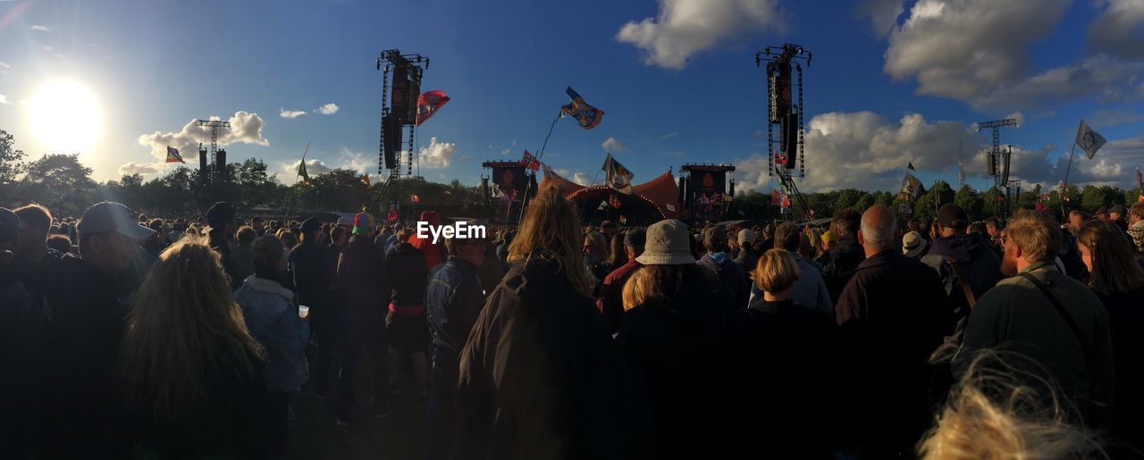 Panoramic view of crowd at music concert against sunny sky