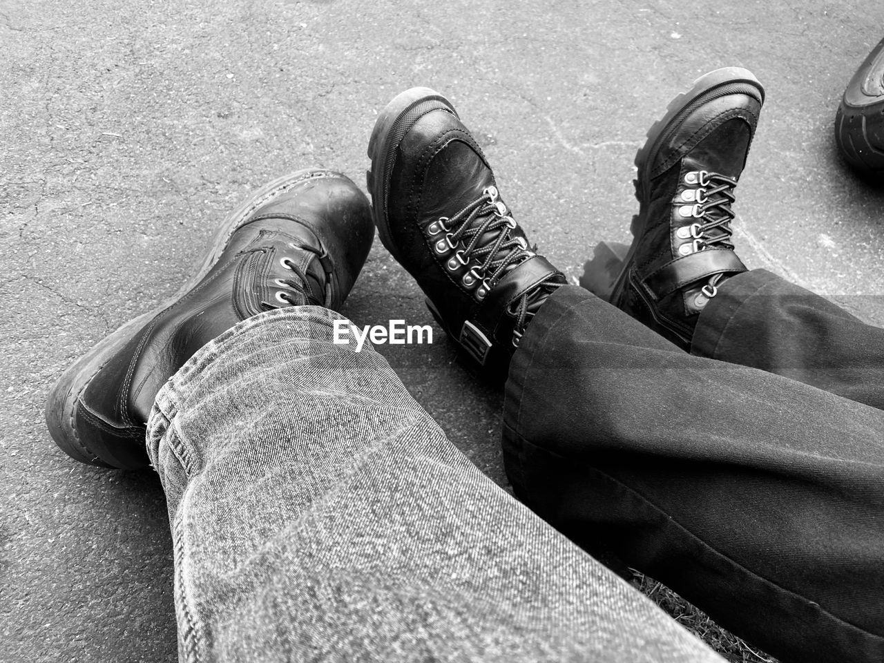 low section, human leg, shoe, black, black and white, lifestyles, personal perspective, monochrome photography, high angle view, footwear, monochrome, one person, white, casual clothing, men, leisure activity, limb, human limb, jeans, day, adult, human foot, standing, relaxation, sitting, outdoors, hand, women, clothing
