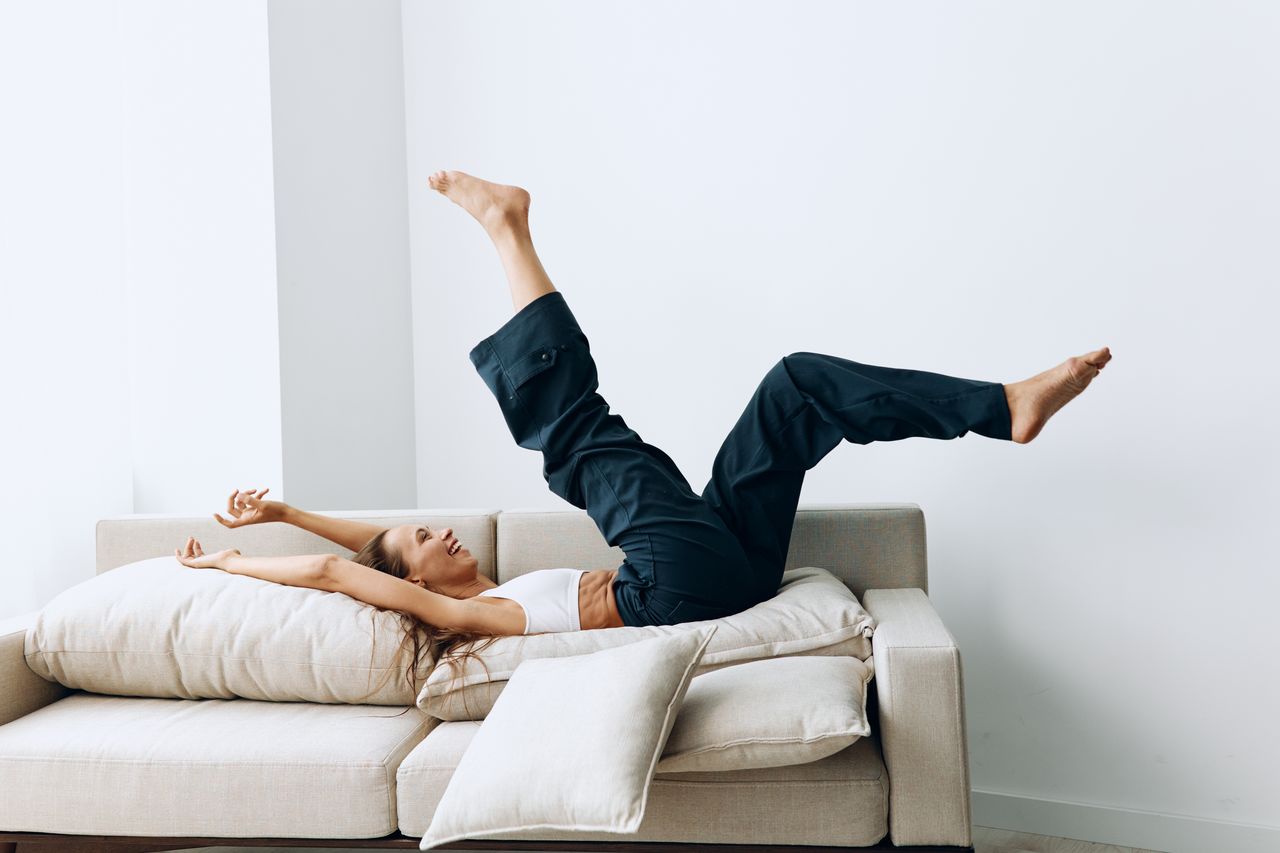 low section of woman exercising on sofa against wall