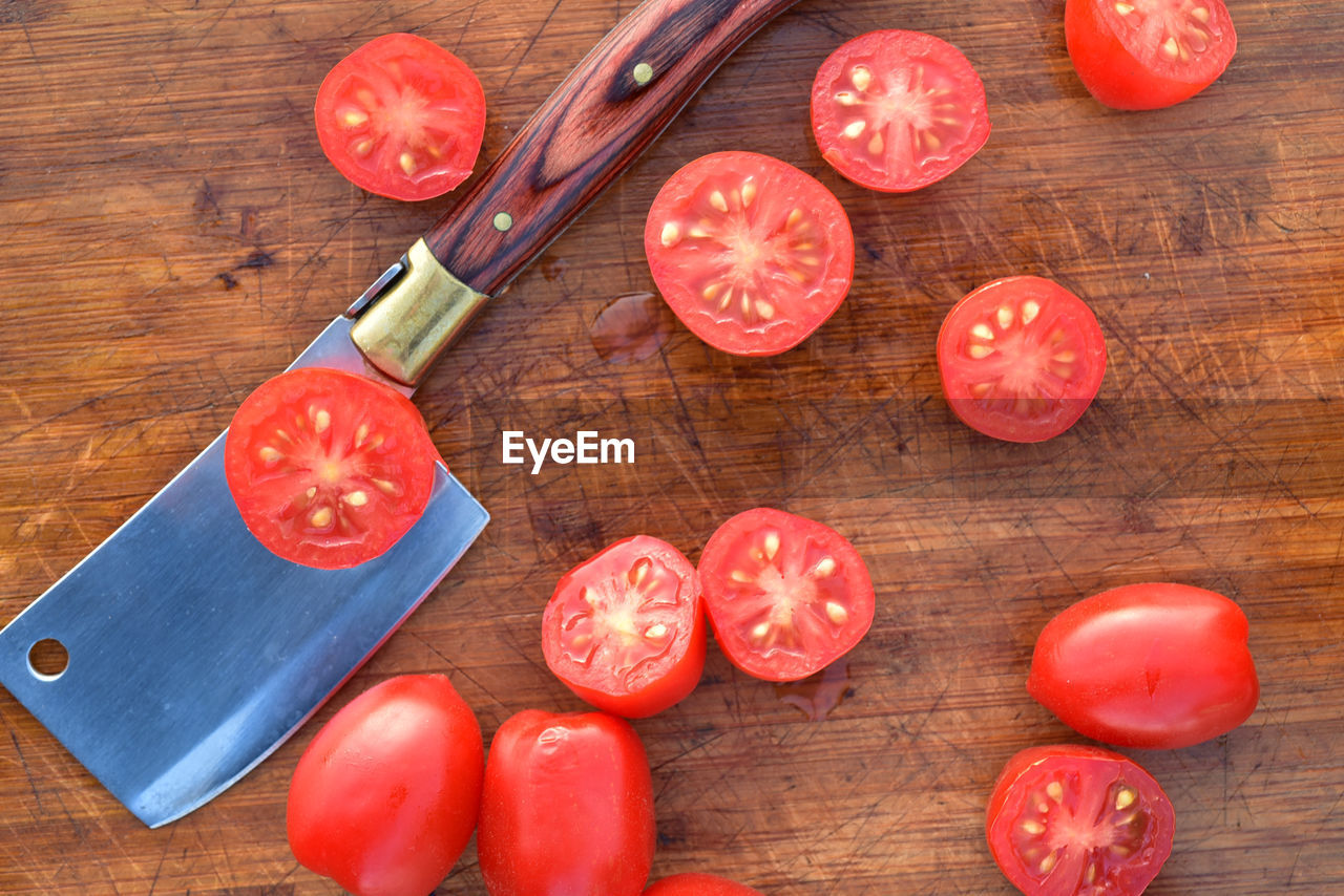 Cut grape tomatoes on wood cutting board with mini cleaver kitchen blade utencil