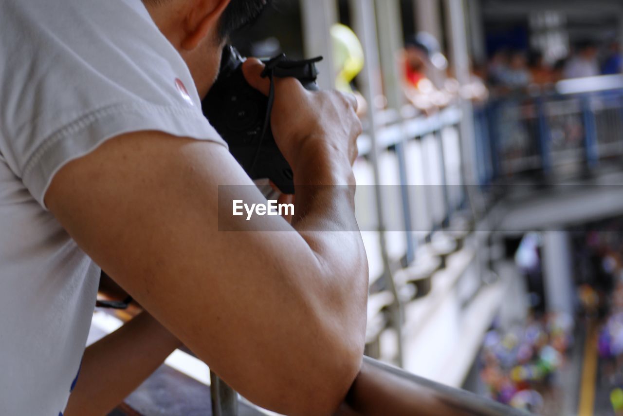 Midsection of man photographing by railing