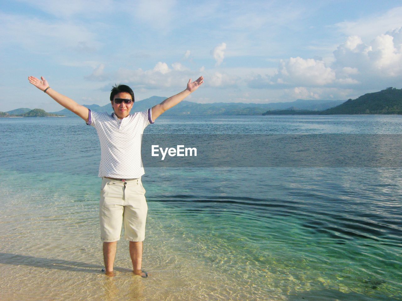 Young man standing on beach against sky