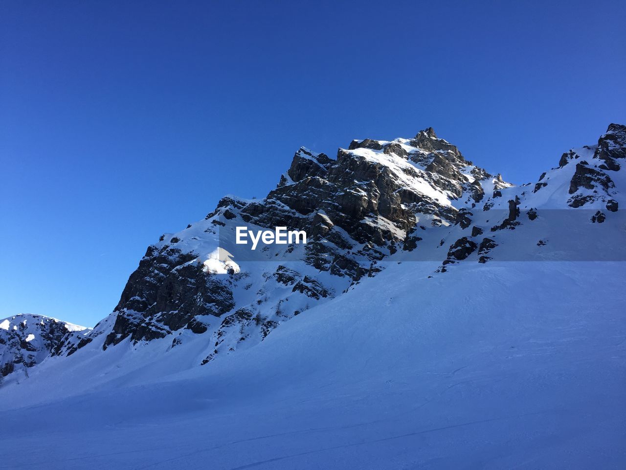 Snow covered mountain against blue sky