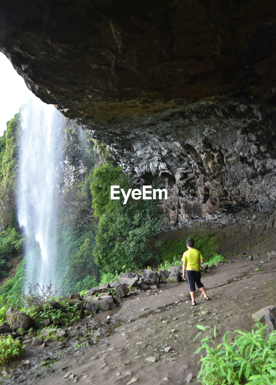 Rear view of boy walking in cave